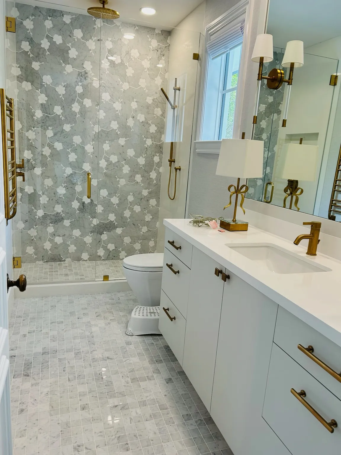 Samuel's bathroom project with patterned shower tile, a white vanity, and brass finishes